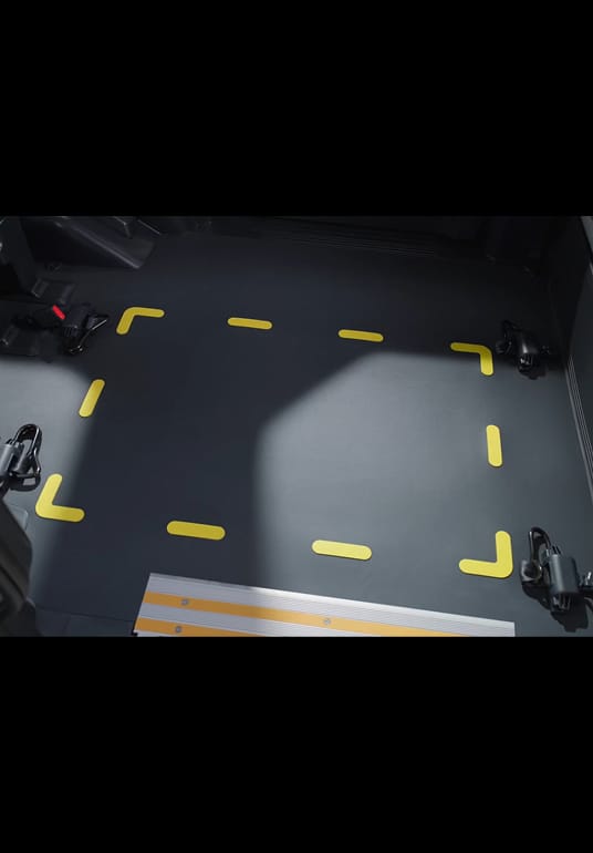 Ein Rollstuhl wird im Kia PV5 WAV positioniert, während eine Person den Rollstuhlrahmen mit dem bodenmontierten Rückhaltesystem sichert.